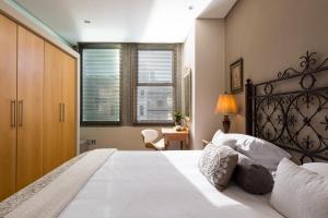 une chambre avec un grand lit avec des draps et des oreillers blancs dans l'établissement #505 Cartwright - Old World Charm, au Cap 19 autres photos