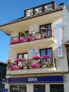 un edificio con flores en los balcones y una cruz en Hotel Victoria en Puebla de Sanabria