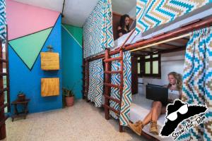 a woman sitting on a bed in a room at Straw Hat Hostel & Rooftop Bar in Tulum