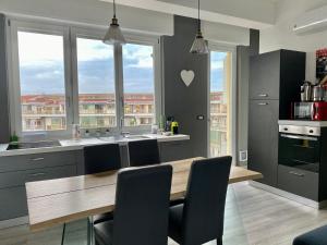 a kitchen with a wooden table and some windows at A Cuneo in Terrazza in Cuneo