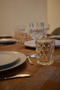 a wooden table with glasses and plates and a spoon at Maison 1747 - Gîtes de Standing en Vieille-ville avec Cour in Boulogne-sur-Mer