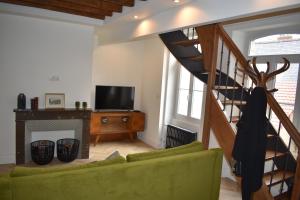 a living room with a staircase and a green couch at Maison 1747 - Gîtes de Standing en Vieille-ville avec Cour in Boulogne-sur-Mer