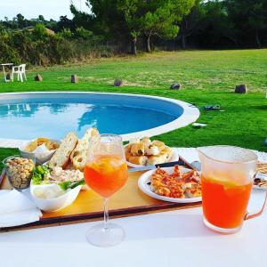 uma mesa com comida e bebidas junto a uma piscina em Bed & Breakfast Il Rosmarino em Bosa