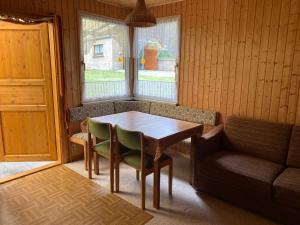 ein Esszimmer mit Tisch und Stühlen und einer Couch in der Unterkunft Waldfrieden Bungalow in Garnsdorf + 14 Fotos