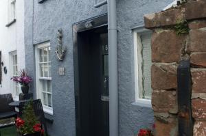 a black front door of a house with a brick wall at Anchor cottage in Brixham