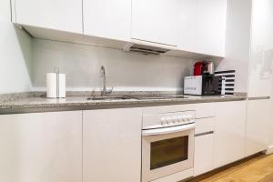 una cocina blanca con armarios blancos y fregadero en Morar Apartments Malasaña, en Madrid