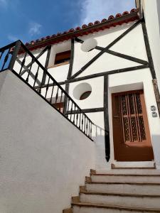 un edificio blanco con una puerta de madera y escaleras en Casa Castillo, en Perales de Tajuña