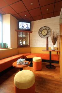 Habitación con sofá, mesas y TV. en Kyriad Hotel Lamballe, en Lamballe