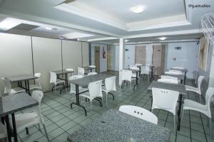 een eetkamer met tafels en witte stoelen en tafels en een stoeltje bij HOTEL ZURIQUE in Patos