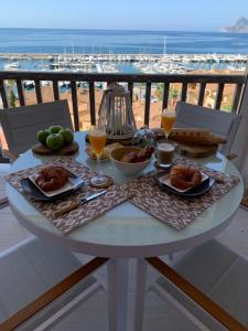 una mesa blanca con comida y bebida y vistas a la playa en BAHIA BEACH - FRONTAAL ZEE- en JACHTHAVEN ZICHT!!!, en Altea