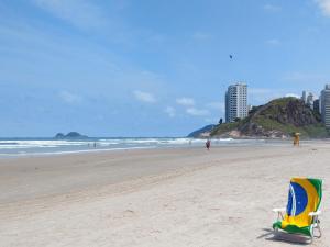 a beach with a chair sitting on the sand at Apt Guarujá Enseada lado praia FAN 1 dorm Tv Netflix Wi-Fi Ar até 5 pessoas in Guarujá +12 photos