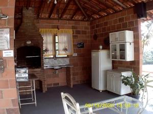 a kitchen with a refrigerator and a brick wall at Terras de Bragança in Bragança Paulista