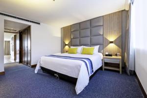 Cette chambre comprend un grand lit avec des oreillers jaunes. dans l'établissement Hotel San Fernando Plaza, à Medellín