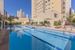 a large swimming pool with chairs and umbrellas next to a building at Mercure Sao Paulo Vila Olimpia in Sao Paulo