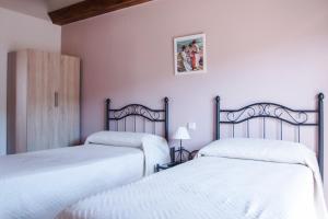 two beds in a room with pink walls at Apartamentos LA PARRA in Buitrago del Lozoya