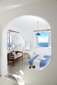 a white room with a bed and a window at Altana Heritage Suites in Imerovigli