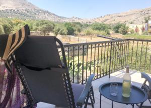 a rocking chair and a table on a balcony at Korali in Symi