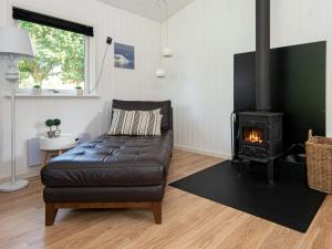 ヒュールスミンネにある6 person holiday home in Juelsmindeのリビングルーム(革張りのソファ、暖炉付)
