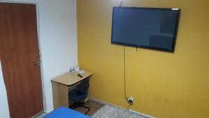 a room with a television on a yellow wall at Hostel Gerais in Belo Horizonte