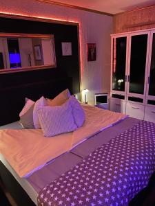 a bedroom with a large bed with purple sheets and pillows at Chez-Ronny in Hamburg