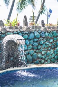 uma parede de pedra ao lado de uma piscina com uma fonte em Olas Permanentes El Zonte em El Zonte