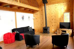 a living room with a couch and a stove at Chalet l'Authentique: Massif, Spa et Plein Air in Petite-Rivière-Saint-François