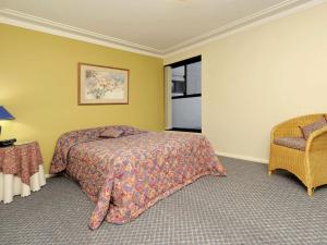 a bedroom with a bed and a chair and a window at Florentine 3 Ground floor Unit with Lift and Sensational Water views in Nelson Bay