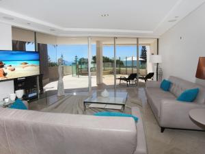 a living room with a couch and a tv at Oceans 201 luxurious beachfront apartment in Mooloolaba