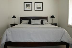 a bedroom with a large white bed with two lamps at Breakaway Apartments in Cowra