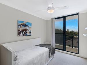 a white bedroom with a bed and a large window at Twin Shores 67 in The Entrance