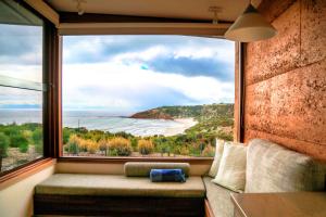 a room with a large window with a view of a beach at Sheoaks in Stokes Bay