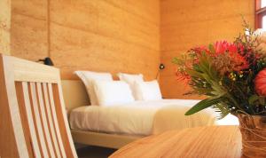 Un dormitorio con una cama y una mesa con un jarrón de flores en Sheoaks, en Stokes Bay