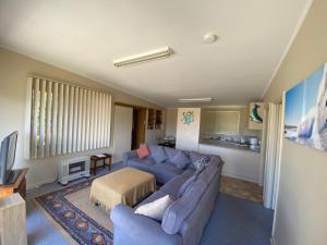a living room with a blue couch and a table at Denhams Beach Cottage in Sunshine Bay +4 photos