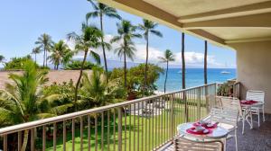 a balcony with a view of the ocean and palm trees at Maui Westside Properties - The Whaler 359 in Kaanapali
