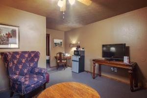 a living room with a tv and a chair and a table at Simmer Motel in Wamego