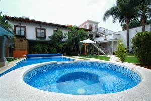 a large blue swimming pool in front of a house at Hotel Concierge Flor y Canto in Tepoztlán