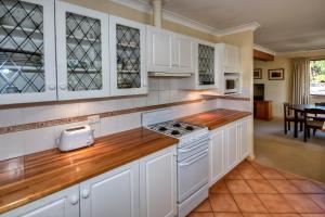 a kitchen with white cabinets and a wooden counter top at Camelot Cottage in Blackheath