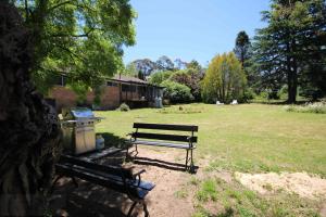 a park bench sitting under a tree in a field at Carawatha in Blackheath