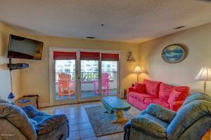 uma sala de estar com um sofá vermelho e cadeiras em LUXURY 2BR OCEAN VIEW CONDO - VILLA CAPRIANI RESORT - SLEEPS UP TO 10 em North Topsail Beach
