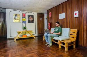 a man sitting on a wooden bench in a living room at Arequipay Backpackers Downtown in Arequipa