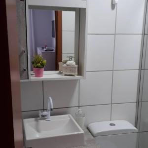a bathroom with a sink and a toilet and a mirror at Apto da Karla em Canela 4 pessoas in Canela