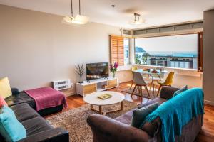 a living room with a couch and a table at Sanctuary On The Beach - Onetangi by Waiheke Unlimited in Onetangi