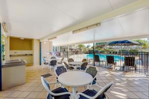 a patio with tables and chairs and a pool at Golden Riviera Absolute Beachfront Resort in Gold Coast