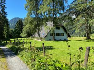 Ein weißes Haus auf einem Feld mit einem Zaun in der Unterkunft Landhaus am Pyhrn in Pyhrn