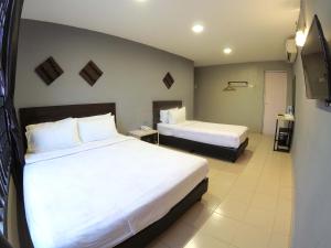 a hotel room with two beds and a television at JV Hotel @ Simpang Ampat in Simpang Ampat