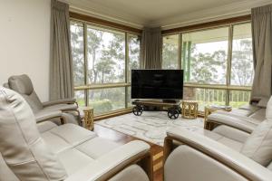 a living room with white chairs and a flat screen tv at Highland View in Mount Victoria