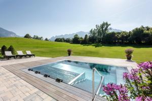 a swimming pool on a patio with a lawn at Klosterhof – Alpine Hideaway & Spa in Bad Reichenhall