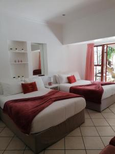 Un dormitorio con dos camas con almohadas rojas. en Knysna N2 Lodge, en Knysna