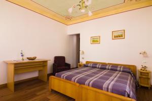 a bedroom with a bed and a desk and a chair at Hotel Centrale in Alleghe