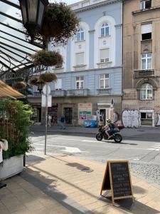 een man die op een motorfiets door een straat rijdt met een bord bij Dragonfly Residence in Belgrado